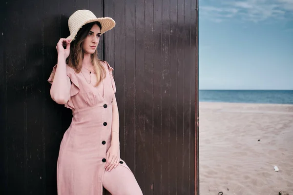 Een jonge vrouw staande op een bruine houten achtergrond met een hoed in een zomerdag — Stockfoto