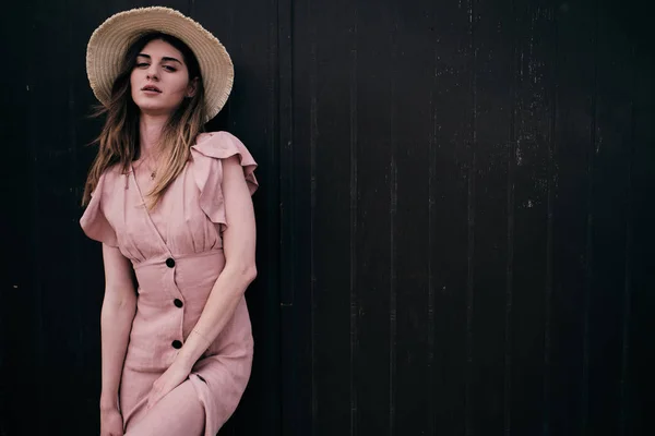 Une jeune femme debout sur un fond de bois brun avec un chapeau dans une journée d'été — Photo