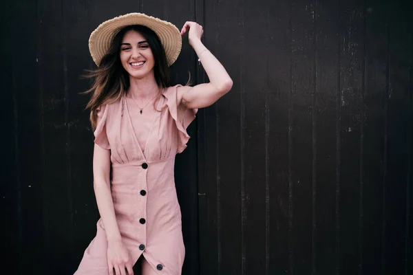 Une jeune femme debout sur un fond de bois brun avec un chapeau dans une journée d'été — Photo