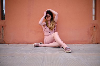 sokakta oturan bir gül elbise ile genç bir kadın