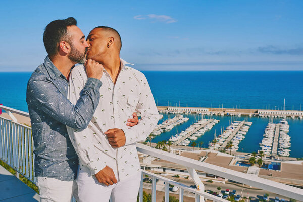 a gay couple on a sunny summer day with the sea behind them