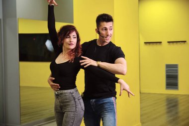 Salsa ve Bachata'ya ders veren genç bir kadın ve bir adam.