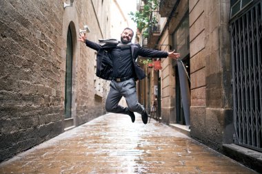 Bir adam şehir sahnesinde ıslak zeminde atlar