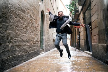 Bir adam şehir sahnesinde ıslak zeminde atlar