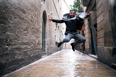 Bir adam şehir sahnesinde ıslak zeminde atlar