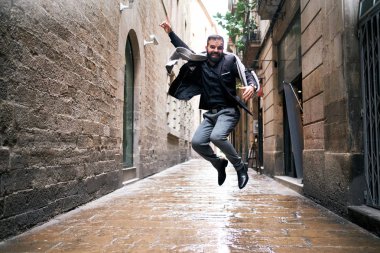 Bir adam şehir sahnesinde ıslak zeminde atlar