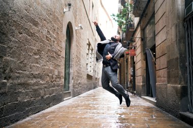 Bir adam şehir sahnesinde ıslak zeminde atlar