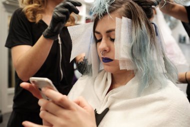 onu cep okurken kadın müşteri saç boyama iki genç kuaför