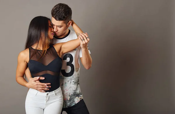Gri bir arka plan içinde salsa ve bachata dans genç bir adam ve kadın
