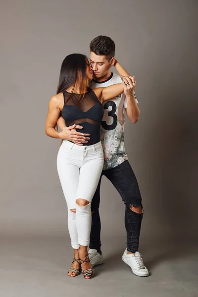 Gri bir arka plan içinde salsa ve bachata dans genç bir adam ve kadın