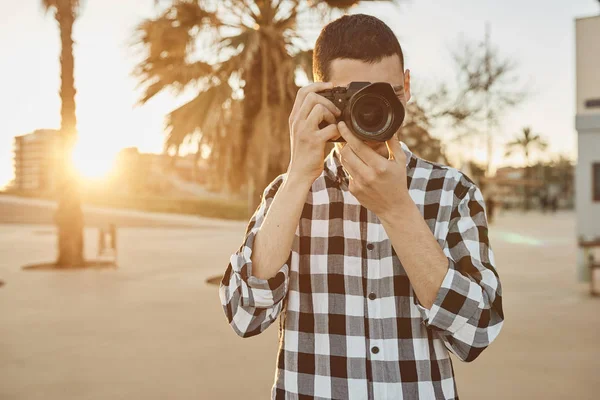 Um jovem fotógrafo com uma câmera vintage ao pôr do sol — Fotografia de Stock