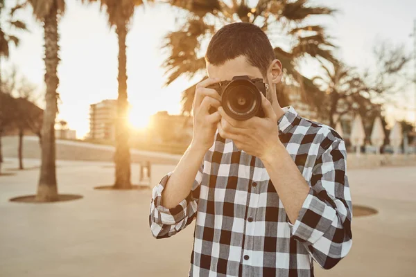 Um jovem fotógrafo com uma câmera vintage ao pôr do sol — Fotografia de Stock