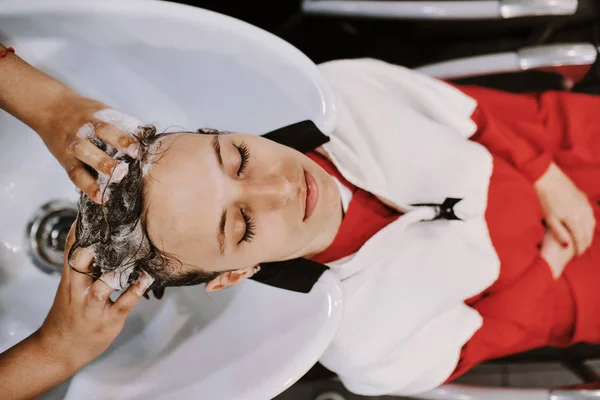 Skönhet och människor koncept - glad ung kvinna med frisör tvätta huvudet vid frisörsalong — Stockfoto