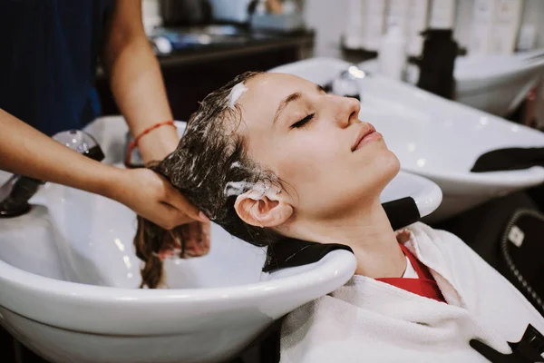 Skönhet och människor koncept - glad ung kvinna med frisör tvätta huvudet vid frisörsalong — Stockfoto