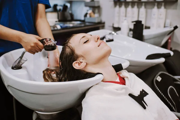 Concepto de belleza y la gente - mujer joven feliz con la cabeza de lavado peluquería en el salón de belleza —  Fotos de Stock