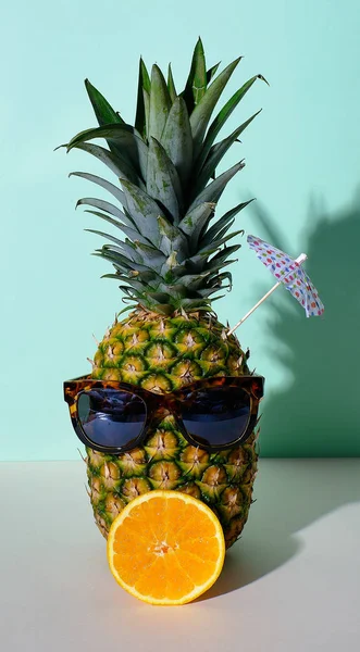 Hälsosam sommar livsstil konceptet med en ananas med glasögon, en apelsin och ett paraply — Stockfoto