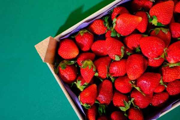 a box of strawberries with a strong green background
