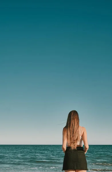 Μια νεαρή γυναίκα σε μια καλοκαιρινή μέρα με ένα γαλάζιο ουρανό-αρνητικό χώρο — Φωτογραφία Αρχείου