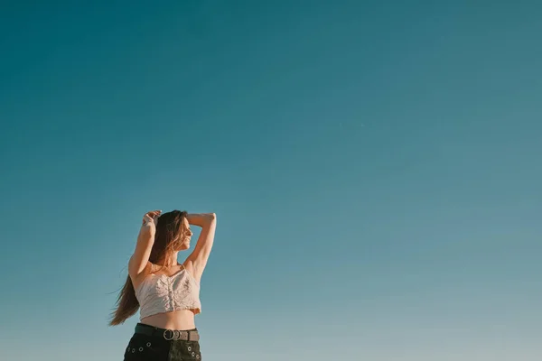 Una mujer joven en un día de verano con un cielo azul - espacio negativo —  Fotos de Stock