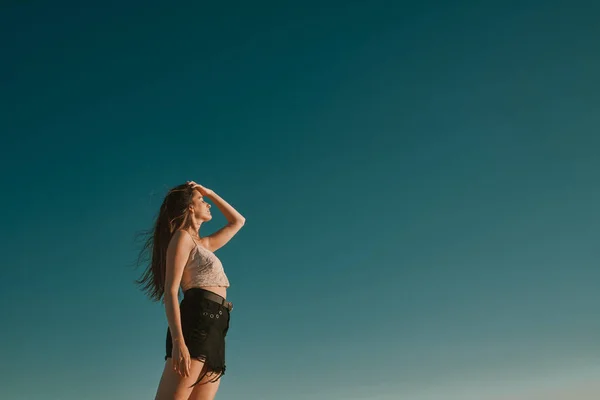 Een jonge vrouw in een zomerdag met een blauwe hemel-negatieve ruimte — Stockfoto