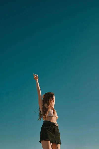 Een jonge vrouw in een zomerdag met een blauwe hemel-negatieve ruimte — Stockfoto