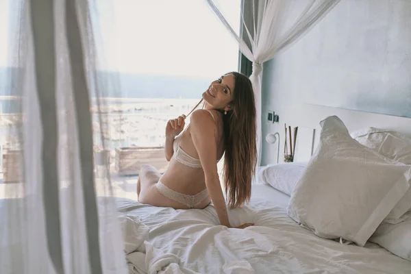 Een jong model in ondergoed zittend voor een raam — Stockfoto