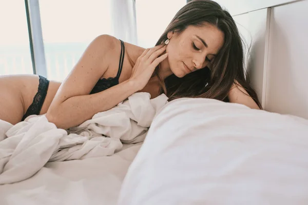 Une femme sexy en sous-vêtements bleus sur son lit — Photo