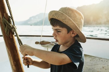 Teknede şapkalı bir çocuk bir denizciyi yaz günü tanıyabilir.