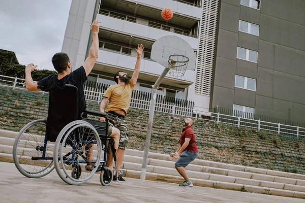 En mann i rullestol spiller basket med venner – stockfoto