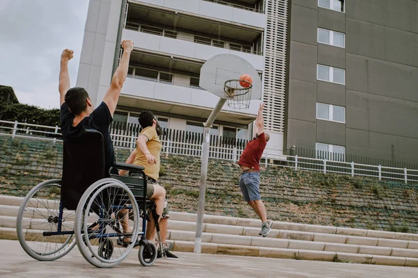 tekerlekli sandalyede bir adam arkadaşlarıile sepet oynar