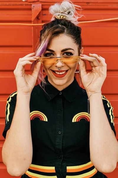 En ung alternativ tjej med gula glasögon och röd bakgrund-livsstilskoncept — Stockfoto