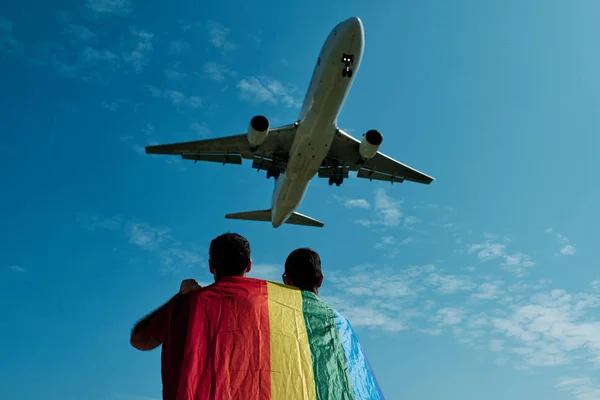 Dos gay hombre con el gay orgullo bandera y un avión — Foto de Stock