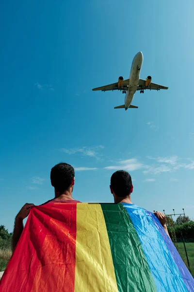 Dos gay hombre con el gay orgullo bandera y un avión — Foto de Stock