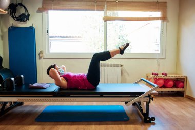 Egzersiz yapan bir grup olgun kadın, sosyal mesafeli Pilates ve Yoga yapıyor ve yüz maskesi takıyor.