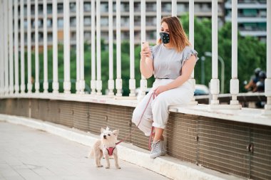 Bir şehir sahnesinde cep telefonunu köpeğiyle kullanan kıvrımlı bir manken.