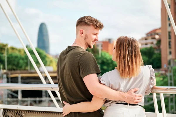 Feliz jovem casal, um homem bonito e um modelo curvilíneo, em uma ponte olhando para o horizonte de Barcelona — Fotografia de Stock