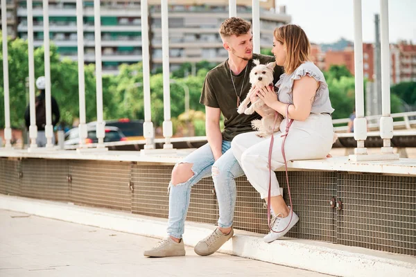 Jovem casal em uma ponte com seu cão em uma cena urbana — Fotografia de Stock