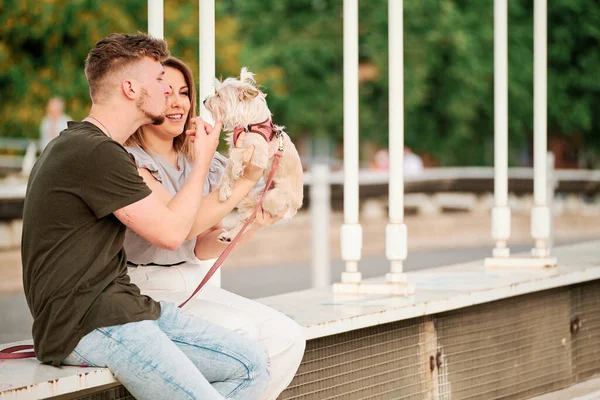 Jovem casal em uma ponte com seu cão em uma cena urbana — Fotografia de Stock