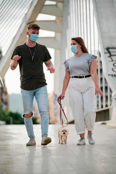 Curvy woman and handsome man wearing face mask taking a walk with their dog - coronavirus concept