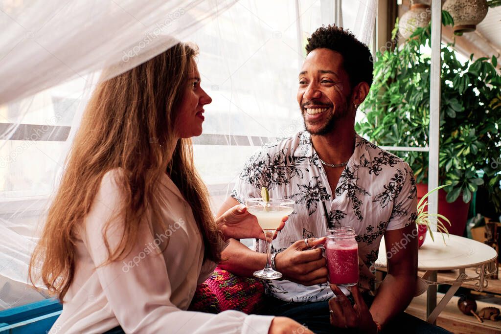 young interracial couple in love drinking a cocktail at the bar