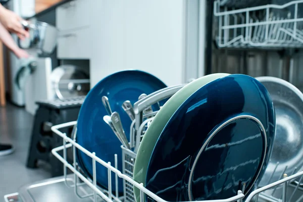 台所用品を整理する女性と一緒に食器洗い機を閉じる — ストック写真