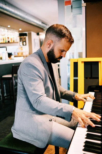 Hombre adulto con un traje gris tocando el piano en el bar —  Fotos de Stock