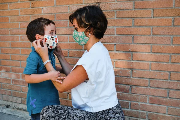 a mother puts a mask to his son in the street