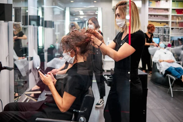 Mujeres en un salón de belleza con distancia social y máscaras protectoras —  Fotos de Stock