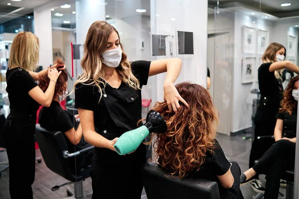 Mujeres en un salón de belleza con distancia social y máscaras protectoras —  Fotos de Stock