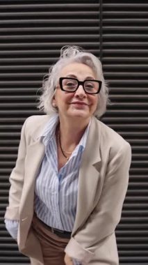 Canlı kıdemli yönetici ağır çekimde neşeyle dans ediyor, gösterişli şehir ortamlarına karşı güven ve başarı ifade ediyor.