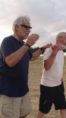 İki yaşlı arkadaş sakin bir parkta yürüyüp sohbet ediyor, hikayelerini ve kahkahalarını ağır çekimde paylaşıyorlar.