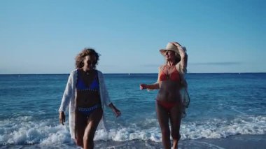 İki olgun kadın sahilde yürümekten zevk alır, hayatın ve arkadaşlığın neşesini kucaklarlar.