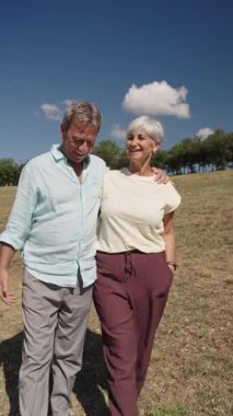 Üst düzey bir çift, emekliliği kucaklayarak ve yavaş çekimde sevgi dolu bir anı paylaşarak, tarlada sakin bir yürüyüşün tadını çıkarıyor.