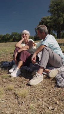 Yaşlı çift boş zamanların tadını çıkarıyor, parkta battaniyeye oturuyor, yavaş çekimde konuşuyor ve gülüyorlar.